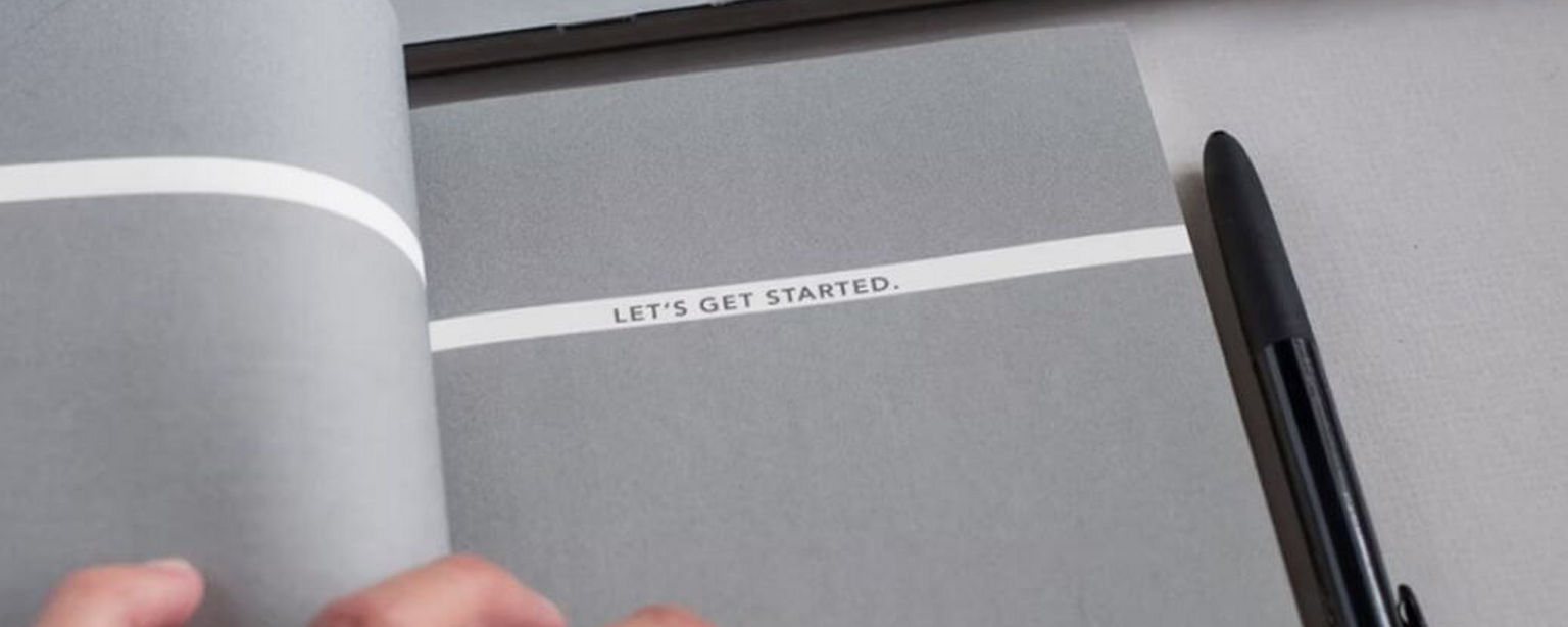“Let’s get started” als Abschnittstitel in einem aufgeschlagenen Buch an einem Arbeitsplatz.